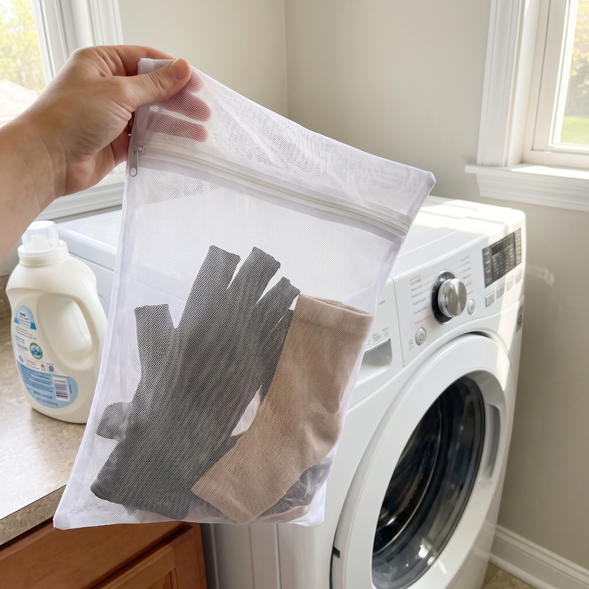 Filet de lavage SovaFlex tenu à la main près du lave-linge